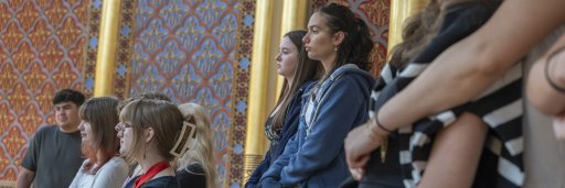 Young school students standing in a synagogue, listening.