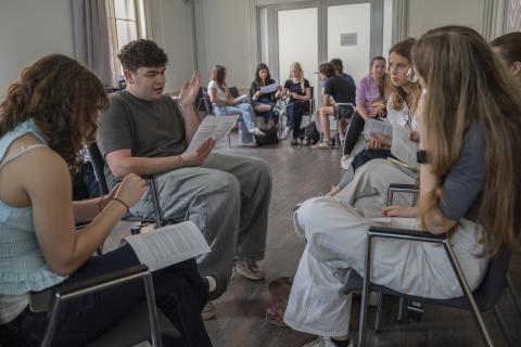 Young school Students sitting in a seminar room, reading and talking