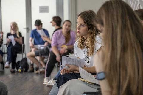 Teenage school Students sitting in a circle of chairs, reading and talking