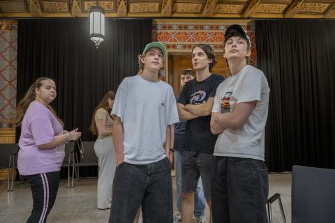 Three male school students standing together in a synagogue, looking around the room