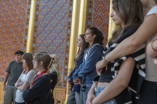 Young school students standing in a synagogue, listening. 